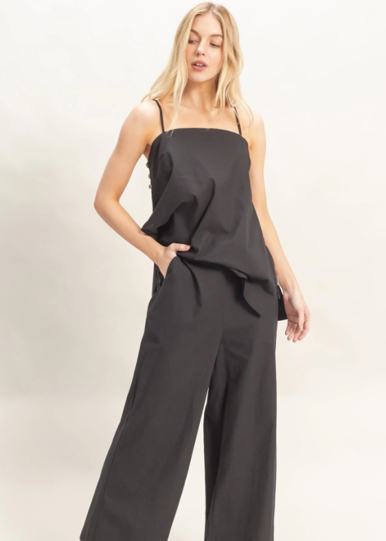 Woman wearing a black jumpsuit on a light background
