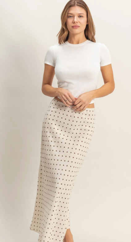 Woman wearing a white top and patterned skirt on a plain background