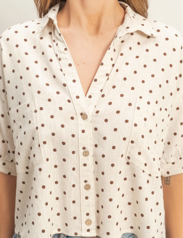 Close-up of a person wearing a white blouse with brown polka dots.