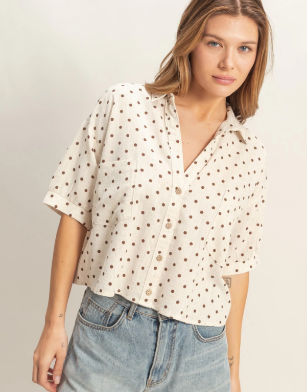 Woman wearing a polka dot blouse and jeans against a plain background