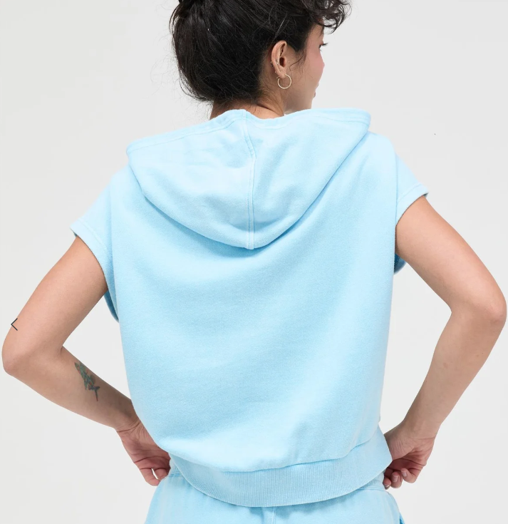 Person wearing a light blue hoodie and shorts set on a plain background