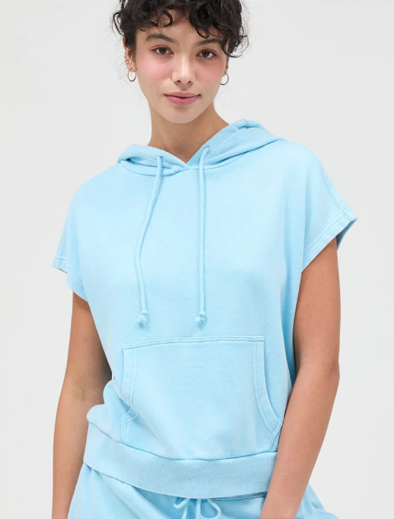Person wearing a light blue hoodie with a plain background