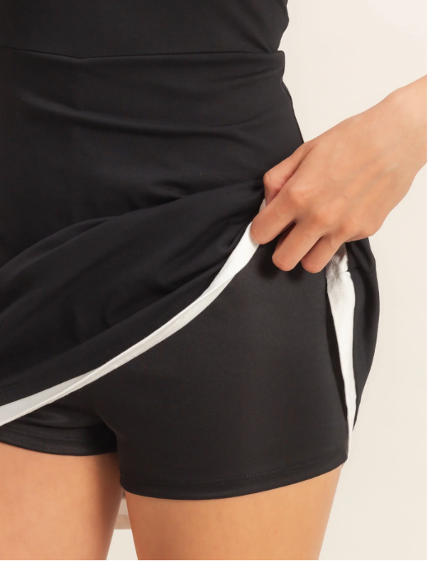Black athletic shorts with a white stripe being adjusted by a hand on a light background