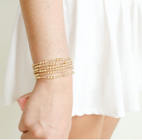 Gold bracelet on a wrist with a white background