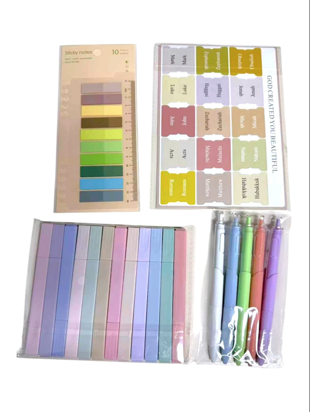 Set of stationery items including colorful markers, a ruler, and a set of colored ribbons on a white background.