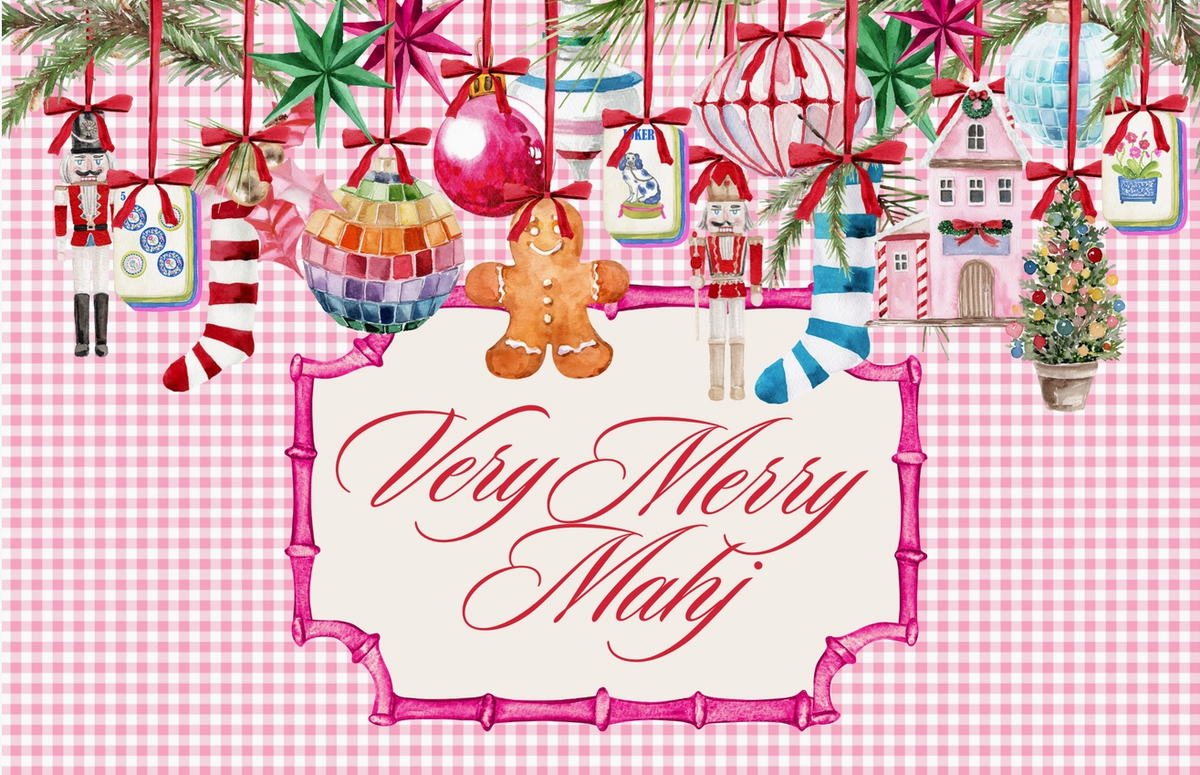 A festive Christmas greeting card design with the text 'Very Merry Mahj' in red script inside a pink bamboo-style frame. The background is pink and white gingham, decorated with hanging ornaments, nutcrackers, candy canes, a gingerbread man, a small house, and a Christmas tree under evergreen branches.