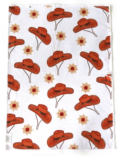 A white tea towel with a repeating pattern of brown cowboy hats and small yellow sunflowers, shown flat against a white background.
