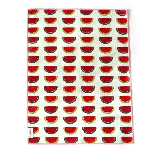 A rectangular kitchen towel with a repeating watermelon slice pattern on a white background, featuring a pink border and a small white label in the bottom-left corner.