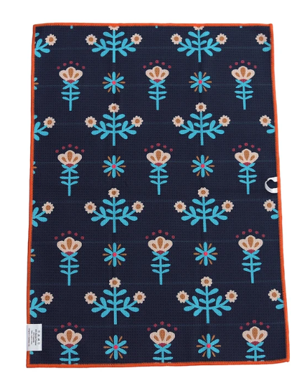 A rectangular woven textile, likely a placemat or small rug, featuring a dark navy blue background with a repeating pattern of light blue and peach flowers with small orange accents. It has a solid orange border and a small white tag on the bottom left.