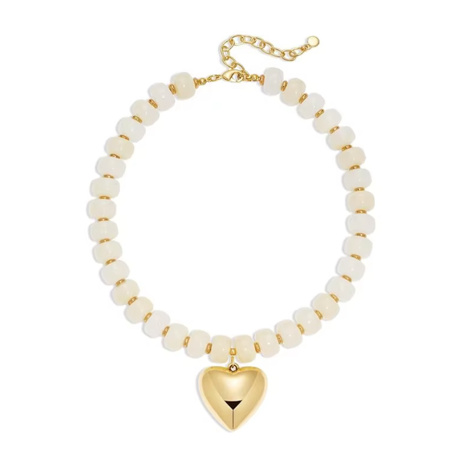 A gold chain necklace with round off-white beads and a polished gold heart-shaped pendant, displayed on a clean white background.