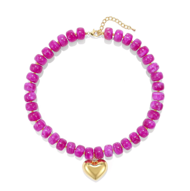 A beaded necklace featuring bright pink marbled beads with a gold heart-shaped pendant and gold chain clasp, displayed on a clean white background.