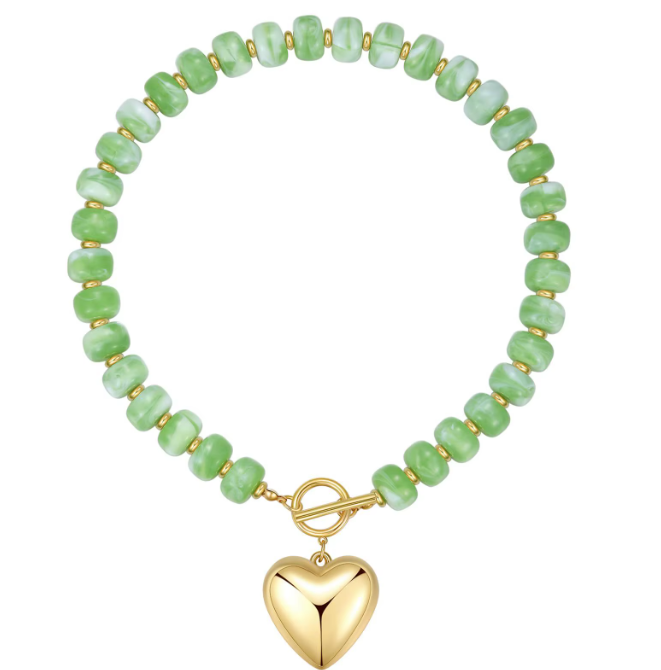 A beaded stretch bracelet featuring light green marbled beads separated by small gold spacer rings, with a polished gold toggle clasp and a dangling gold heart charm, shown on a plain white background.