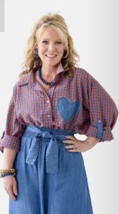 A woman modeling a red and blue plaid button-up shirt with a blue denim heart patch on the chest, paired with a blue denim skirt, against a plain white background.