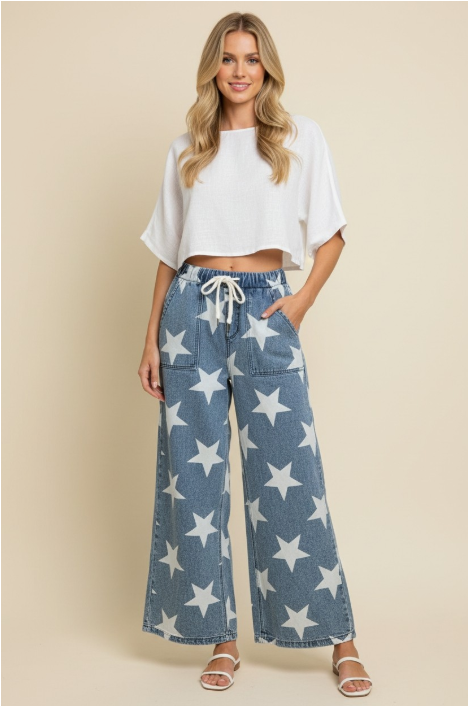 Woman wearing a white top and blue star-patterned pants on a beige background