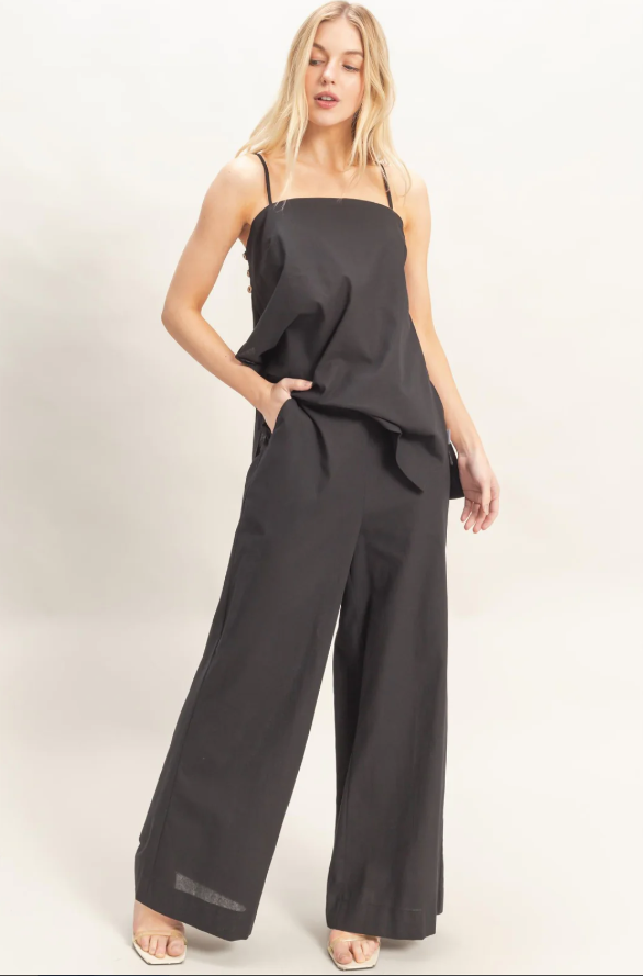 Woman wearing a black strapless top and wide-leg pants on a white background