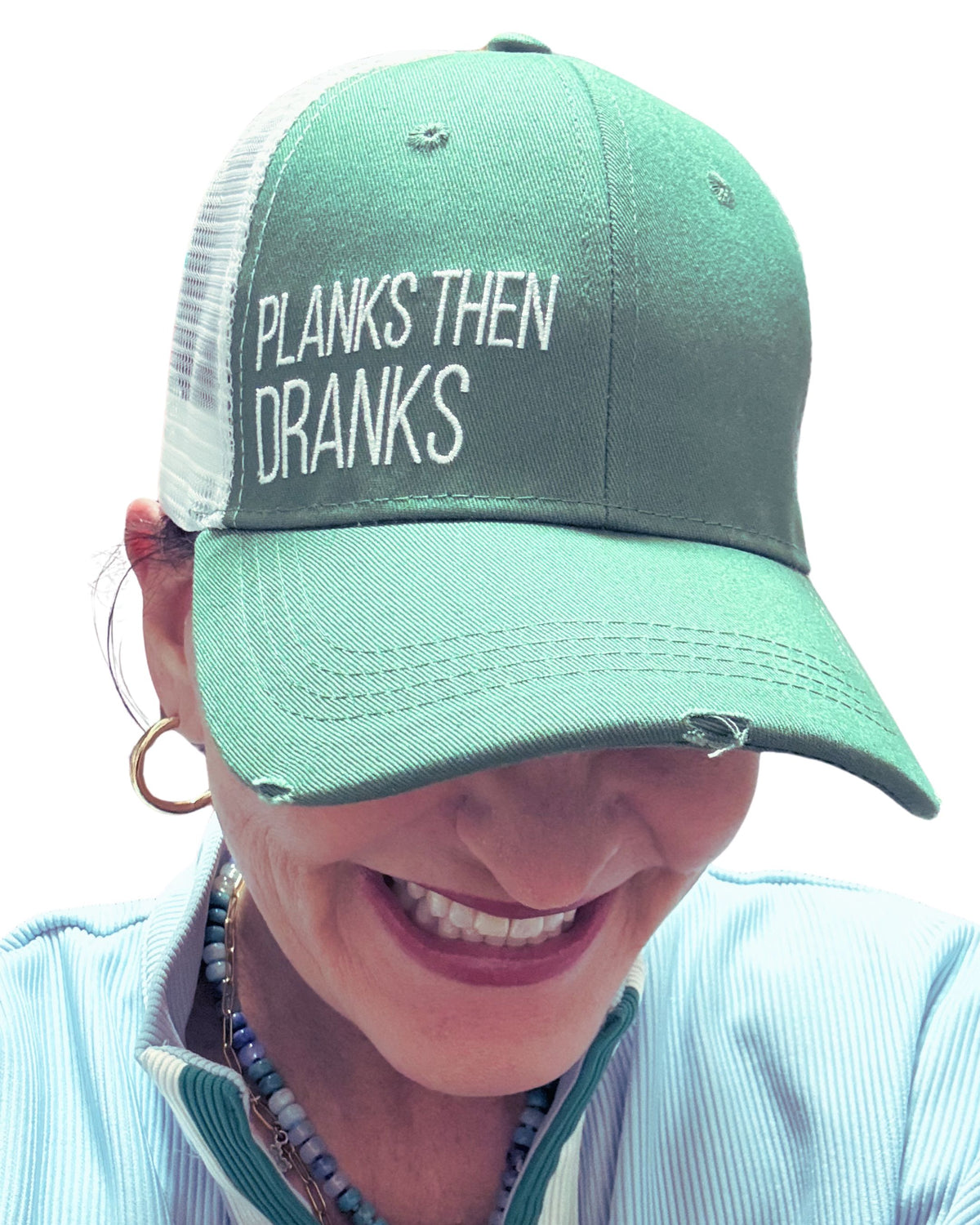 Person wearing a green cap with 'PLANKS THEN DRANKS' text on a white background