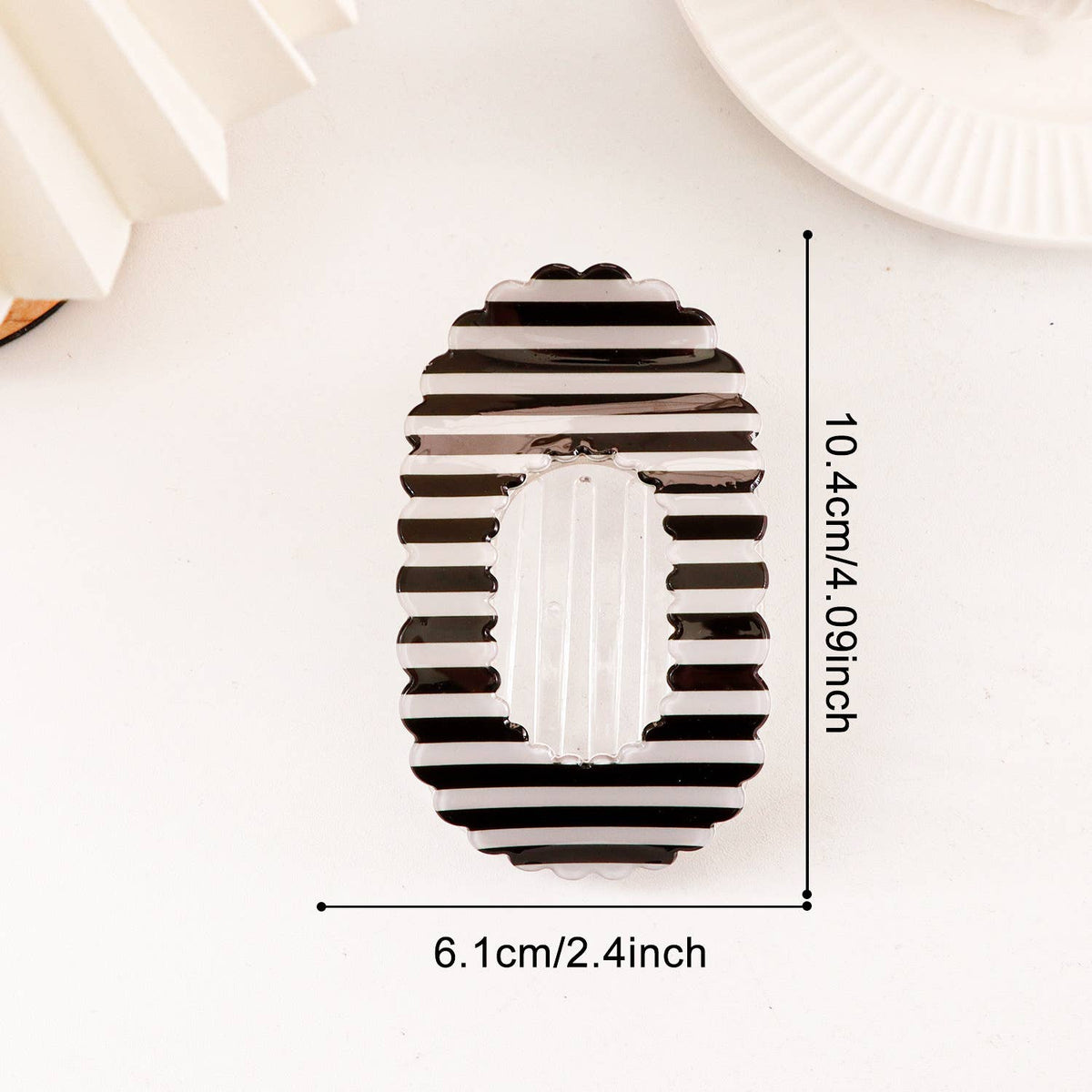 A striped black and white hair claw clip shown on a white background with dimension lines indicating a height of 10.4cm (4.