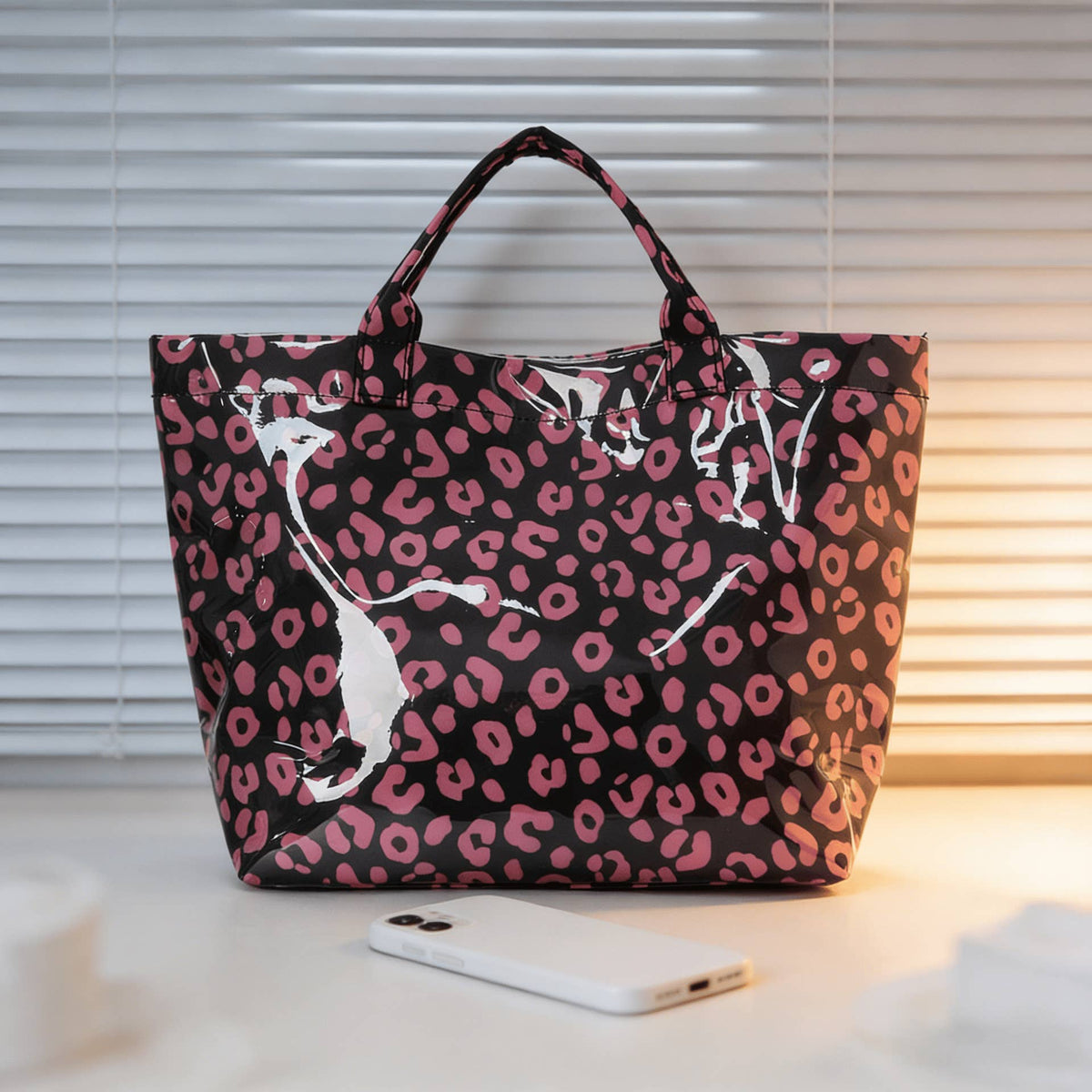 Pink leopard print tote bag on a light surface with a blurred background