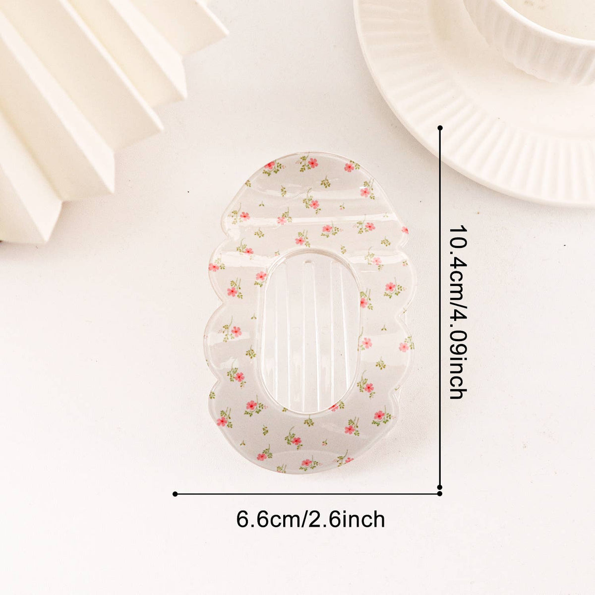 A translucent white sanitary pad with a small pink and green floral pattern, shown with dimension lines indicating a width of 6.6cm (2.