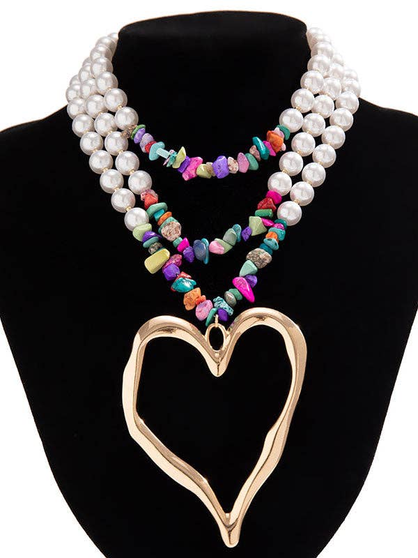 Necklace with pearl and multicolored bead strands and a gold heart pendant on a black stand.