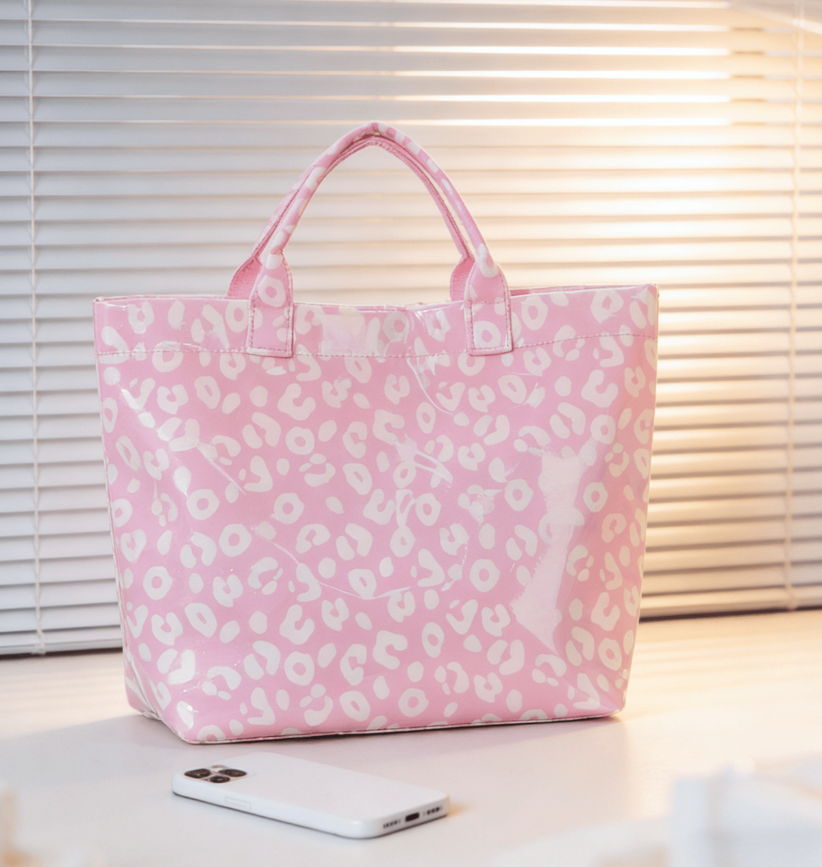Pink tote bag with white leopard print pattern on a light surface.