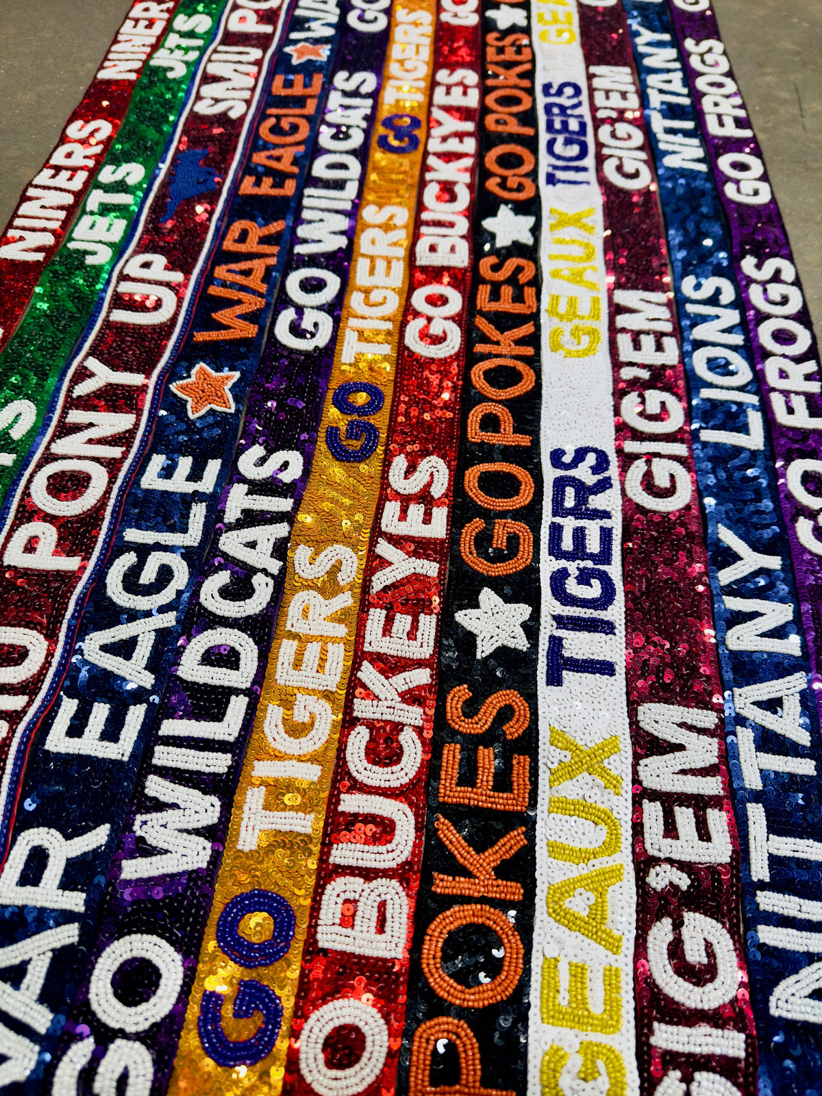 Colorful woven belts with various team names and logos.