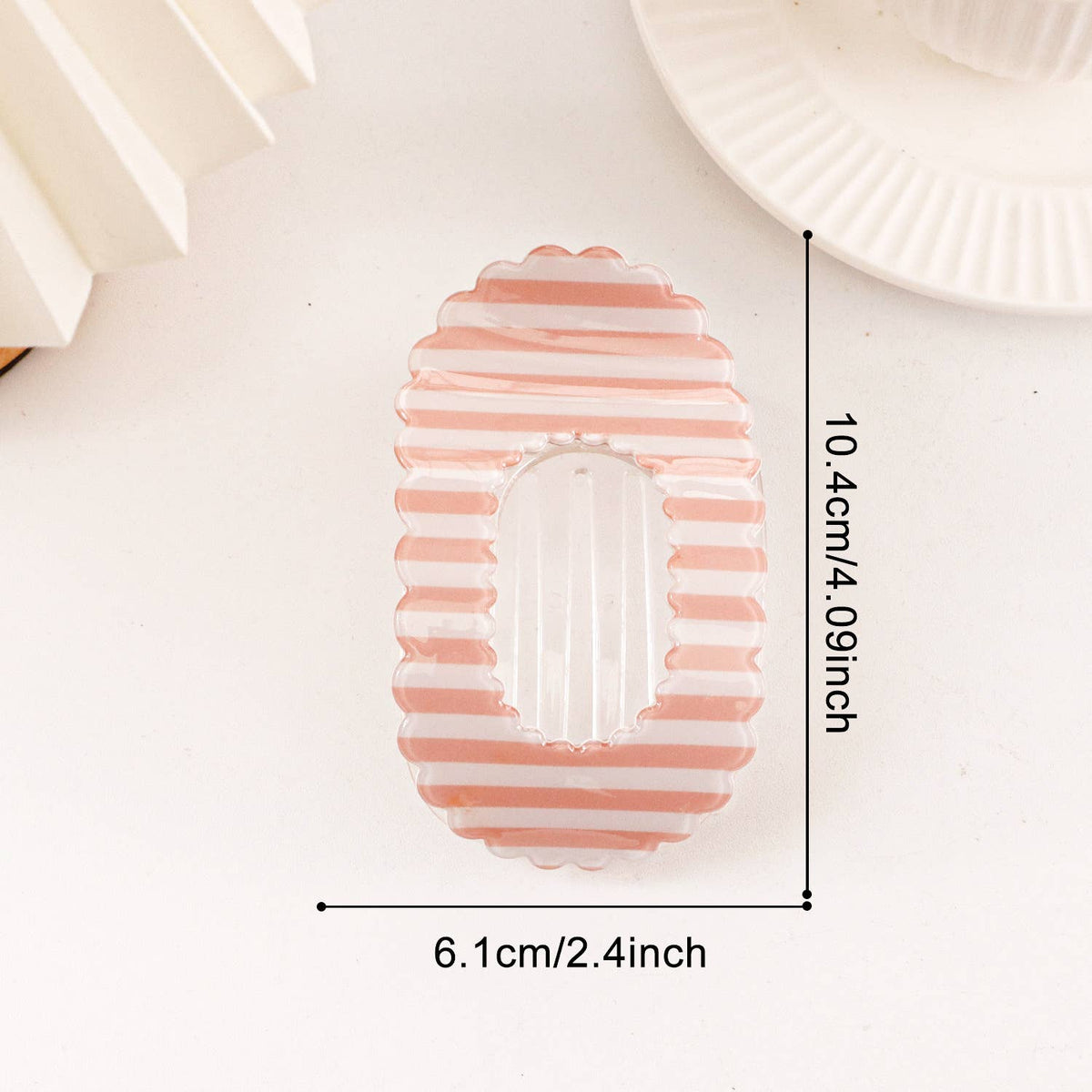 A pink and white striped oval plastic mold with a scalloped edge and a central cutout, shown on a white background with dimension lines indicating 10.4cm in height and 6.