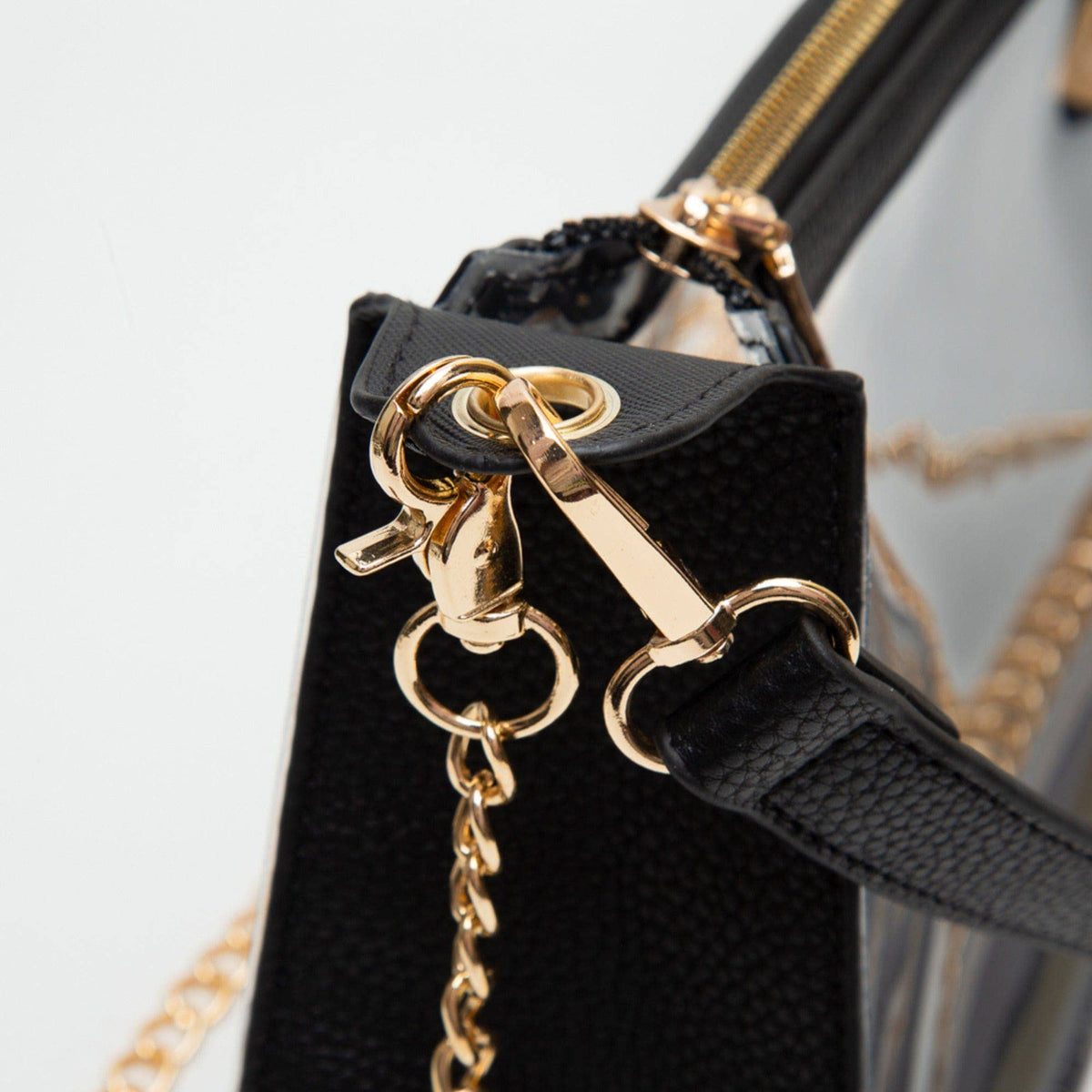 Black handbag with gold hardware and chain detail on a light gray background
