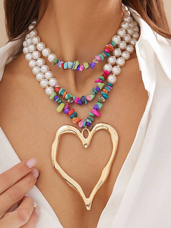 Necklace with heart pendant and colorful beads on a person wearing a white shirt.