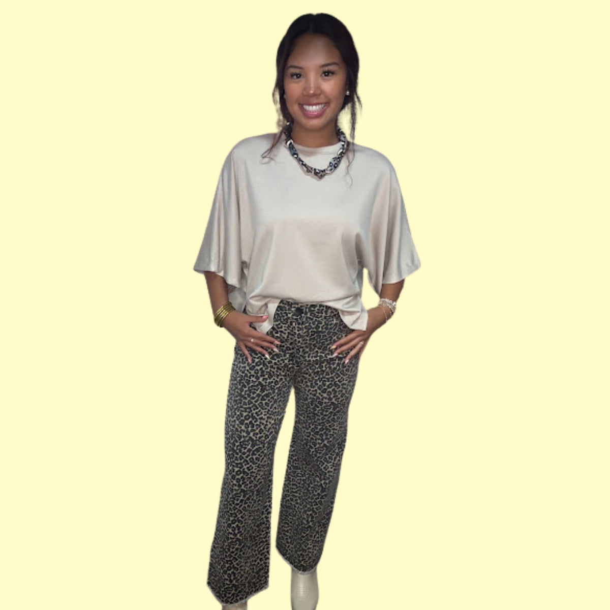 Woman wearing a light-colored top and patterned pants on a plain background