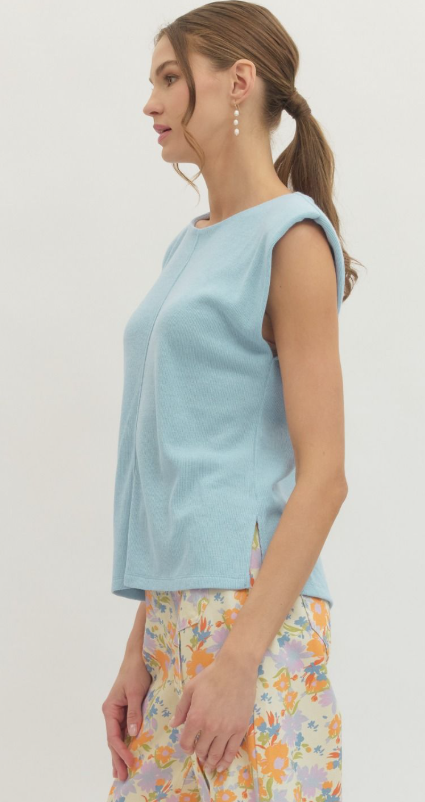 Woman wearing a light blue sleeveless top with a plain background